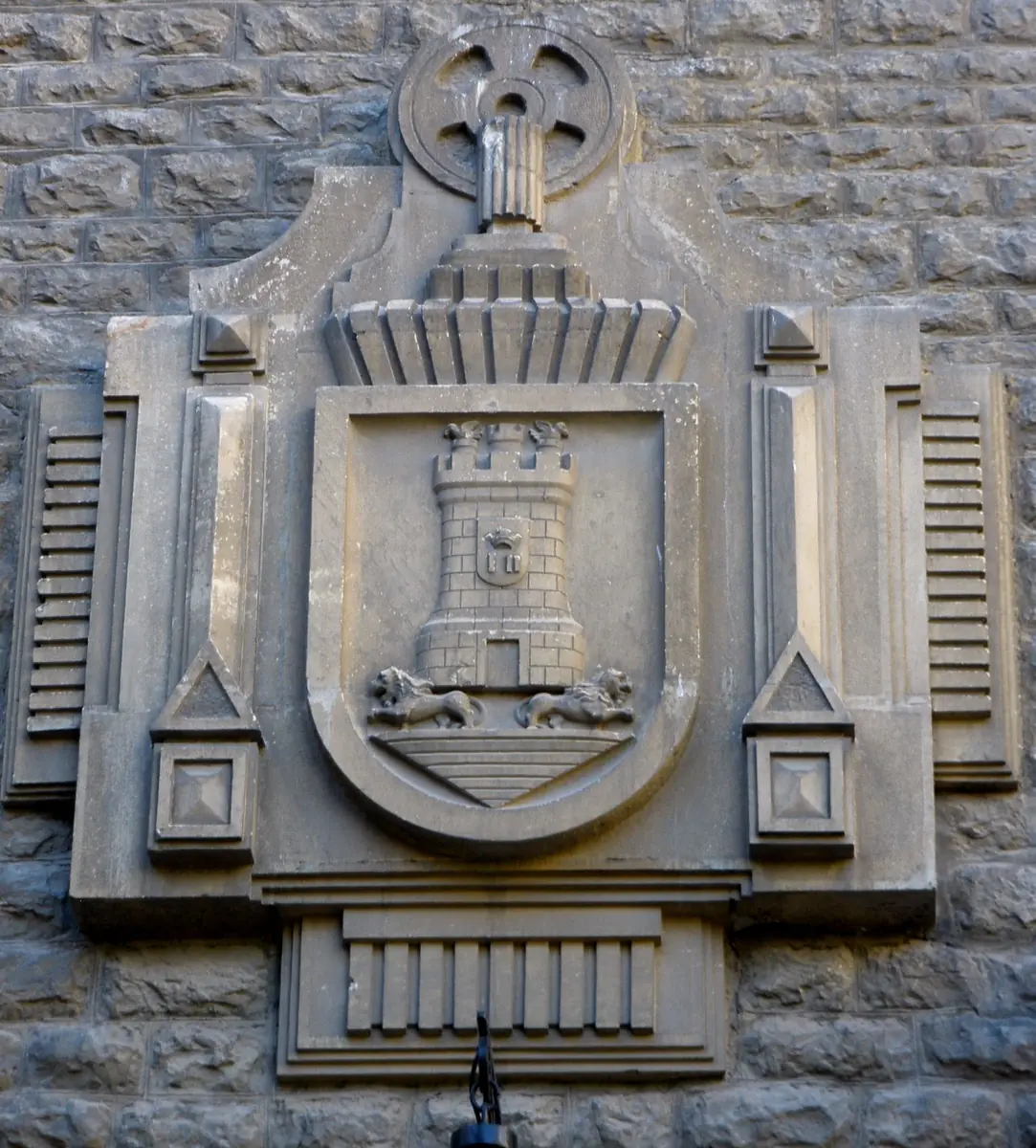 Escudo con una torre sobre un montículo y dos leones en la base en la Escuela de Artes y Oficios, Vitoria-Gasteiz.