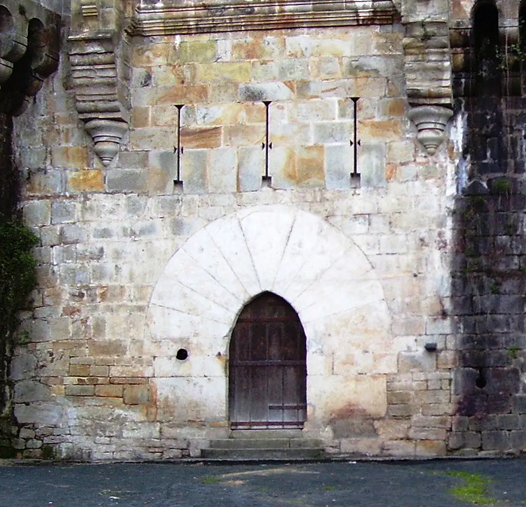 Puerta de arco apuntado del castillo de Butrón (reconstrucción del siglo XIX), con grandes ménsulas que vuelan en lo alto del muro.