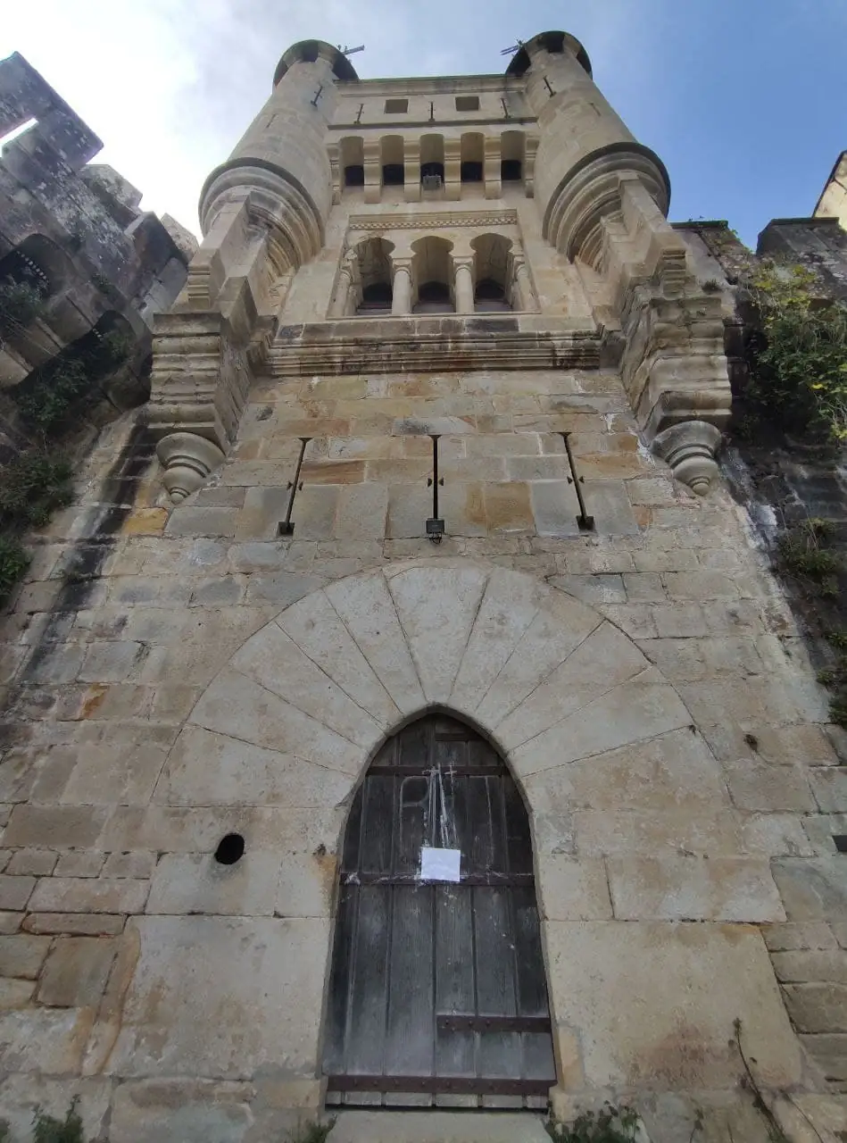 Torre de entrada del castillo de Butrón vista desde abajo: arco apuntado, ventanas y torrecillas de esquina.