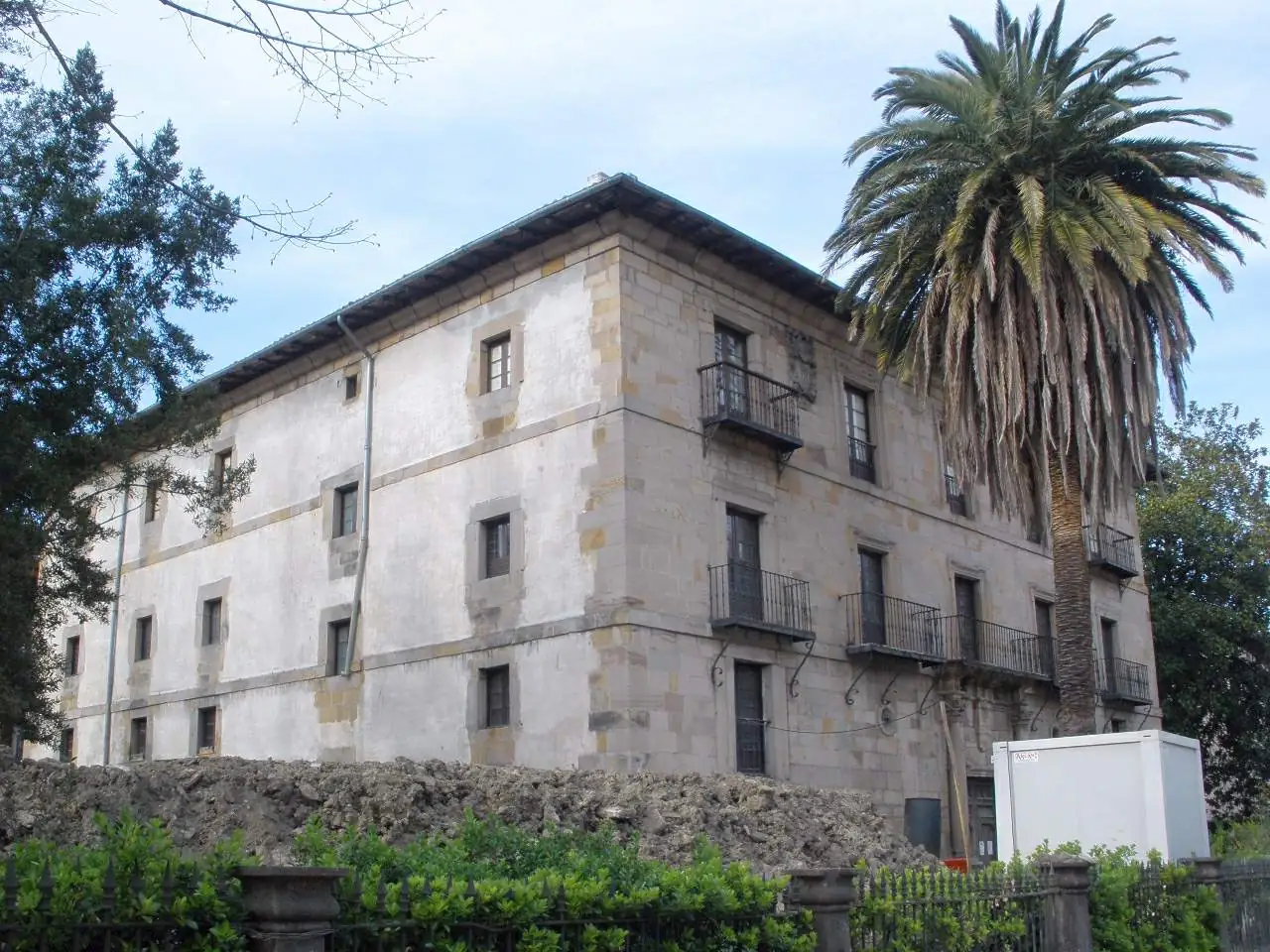El palacio de Horcasitas visto desde un lateral, con una palmera delante.