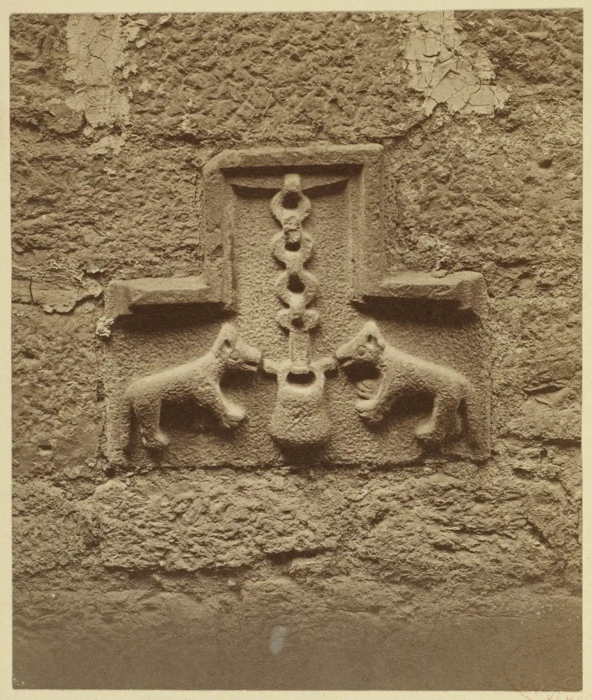 Escudo de los Loiola sobre la puerta de entrada de la casa, con dos lobos a ambos lados de una caldera colgada de una cadena, fotografiado por Jean-Auguste Brutails.