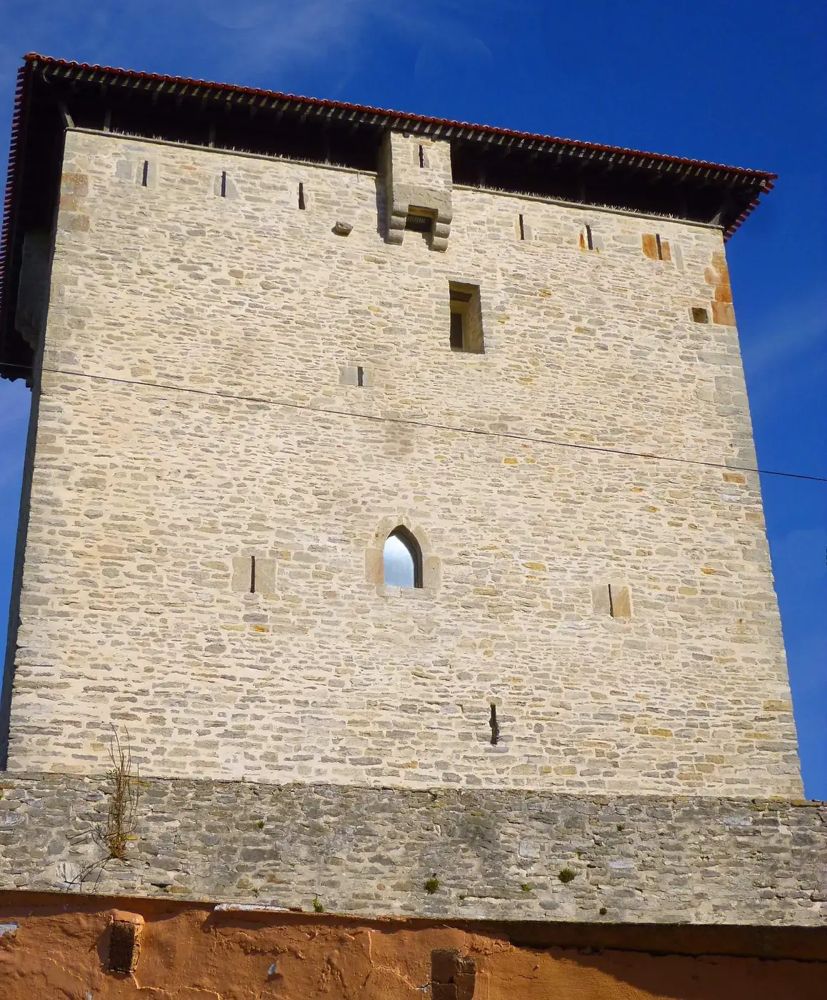 Parte alta de la torre de Mendoza, con una ventana de arco apuntado y la cornisa bajo el tejado.