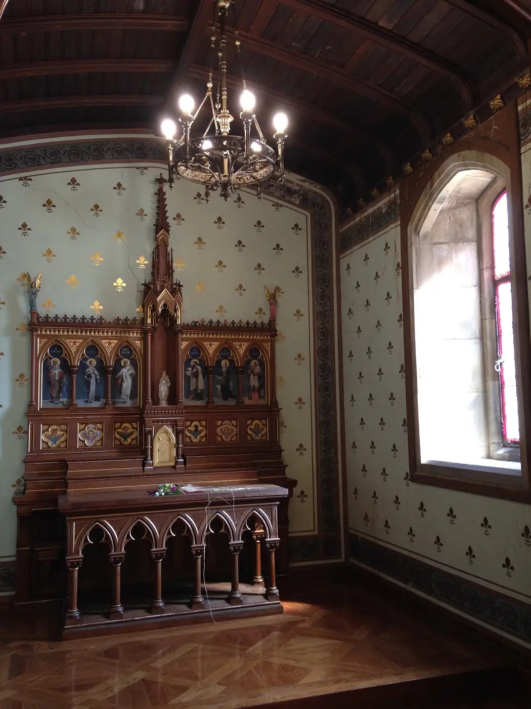 Capilla del palacio de Miramar con un altar neogótico de madera y paredes decoradas con flores de lis.