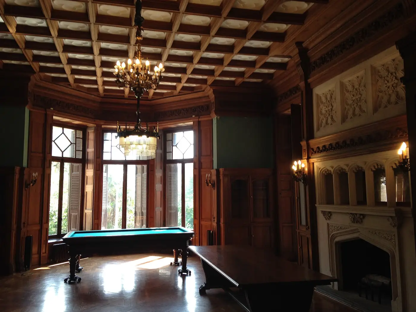 Sala del palacio de Miramar con techo de casetones, chimenea de piedra y ventanal mirador, identificada como la biblioteca y sala de billar.