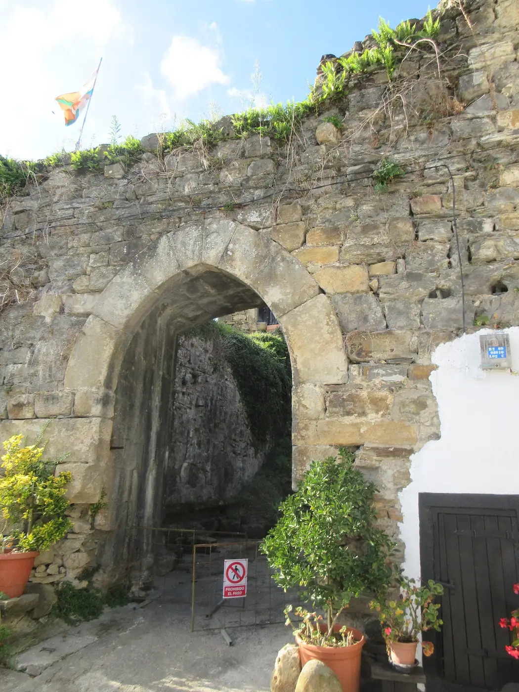 Puerta y muro del recinto de la torre de Muxika, con un arco de piedra.
