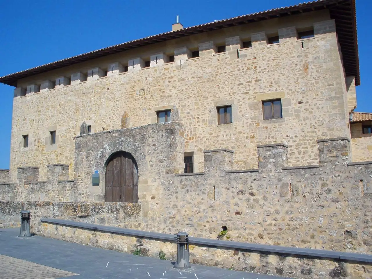 Fachada de la torre-palacio de los Varona con el portal de arco apuntado y el muro almenado por delante.