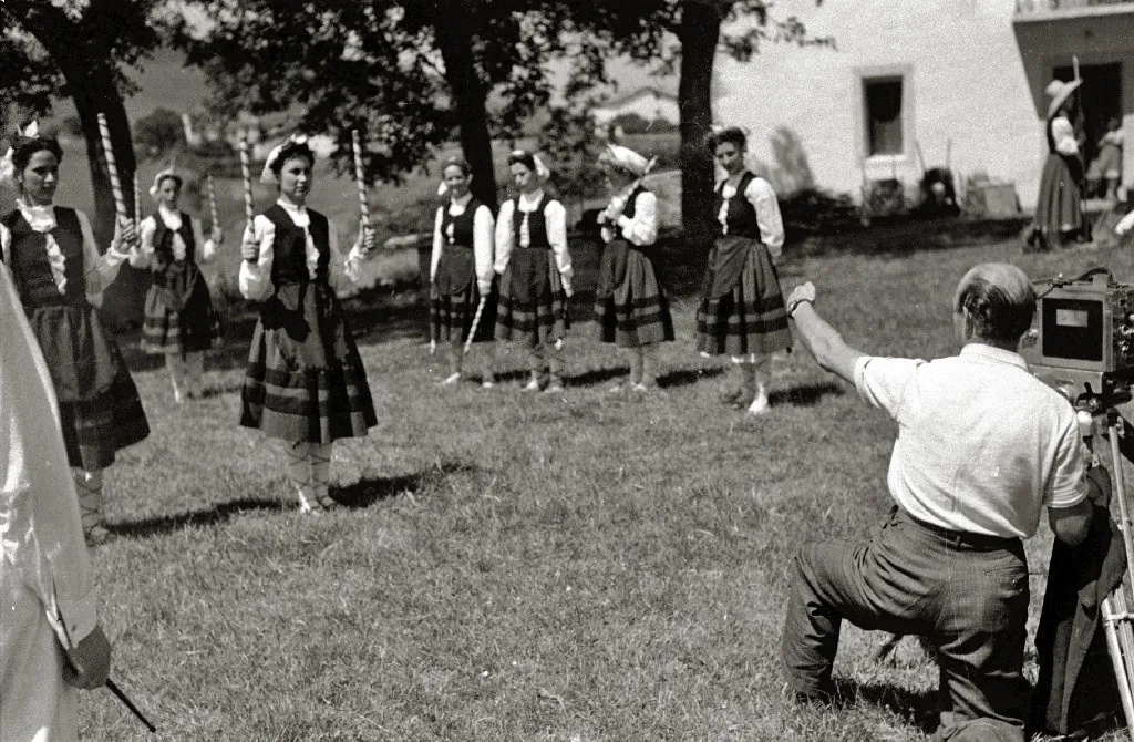 Un grupo de bailarinas con traje tradicional en una campa de Igueldo, ante un operador con una cámara de cine, en el rodaje de unas danzas vascas.