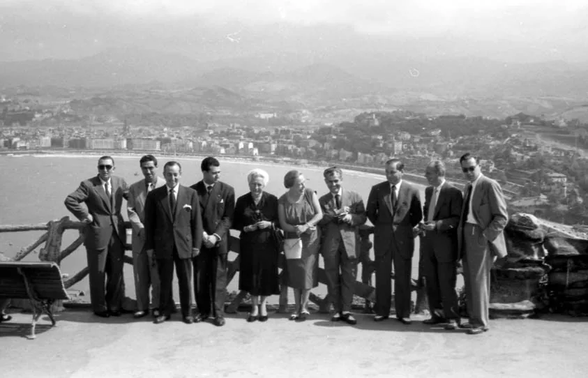 Un grupo de hombres y mujeres posa en el mirador del monte, con la bahía y la ciudad al fondo. El archivo los describe como representantes de ventas junto a la familia Niessen.